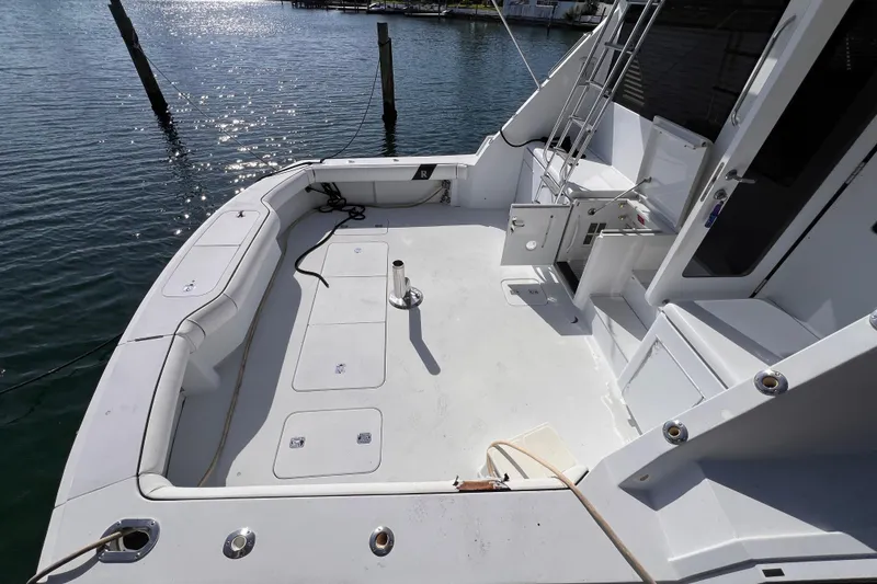 Slide: The Image of 2001 Hatteras 65 Convertible yacht deck with seating and ladder, docked by the water. - 8