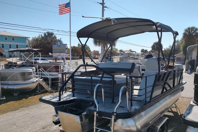 Slide: The Image of 2026 Sylvan Mirage X3 CLZ DH pontoon boat displayed outdoors with American flag. - 2