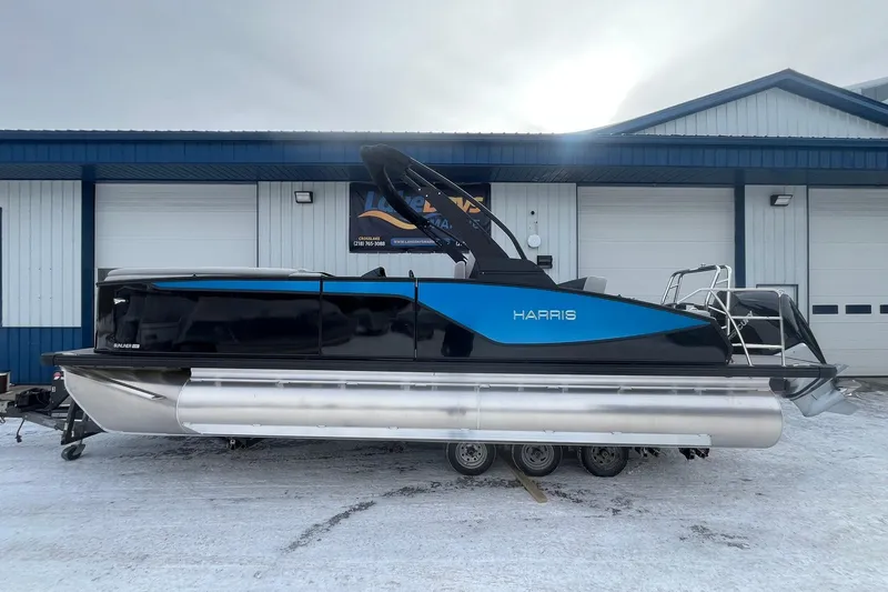 The Image of 2026 Harris Sunliner 230 pontoon boat in blue and black, parked on a snowy surface. - 1