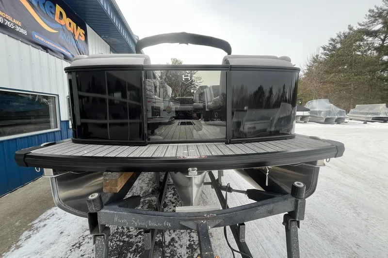 Slide: The Image of 2026 Harris Sunliner 230 pontoon boat on trailer, parked outside dealership in winter. - 6