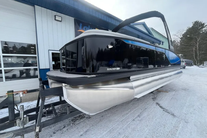 Slide: The Image of 2026 Harris Sunliner 230 pontoon boat on trailer, parked outside dealership in winter. - 7