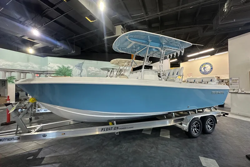The Image of 2026 Bluewater 23T boat on trailer in showroom, featuring sleek blue design. - 1
