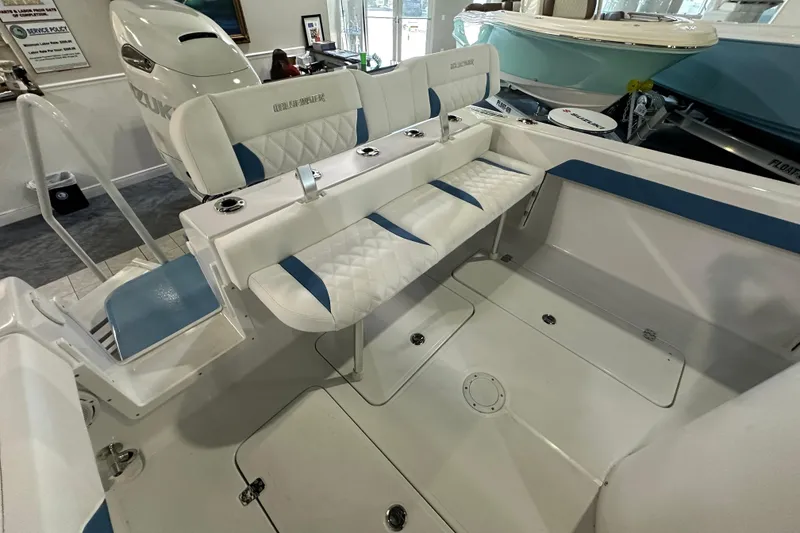 Slide: The Image of 2026 Bluewater 23T boat interior with white and blue seating, Suzuki engine visible. - 17