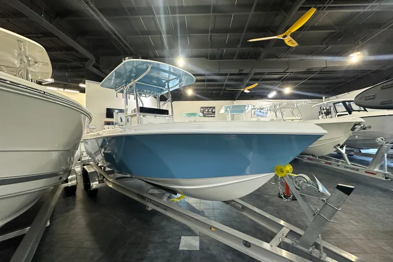 Slide: The Image of 2026 Bluewater 23T boat displayed indoors on a trailer. - 2