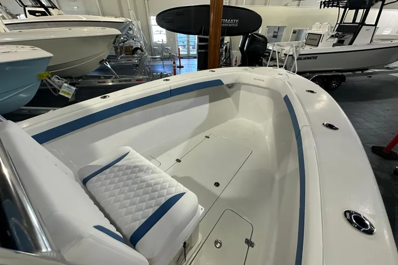 Slide: The Image of 2026 Bluewater 23T boat interior with white and blue seating, displayed in showroom. - 7