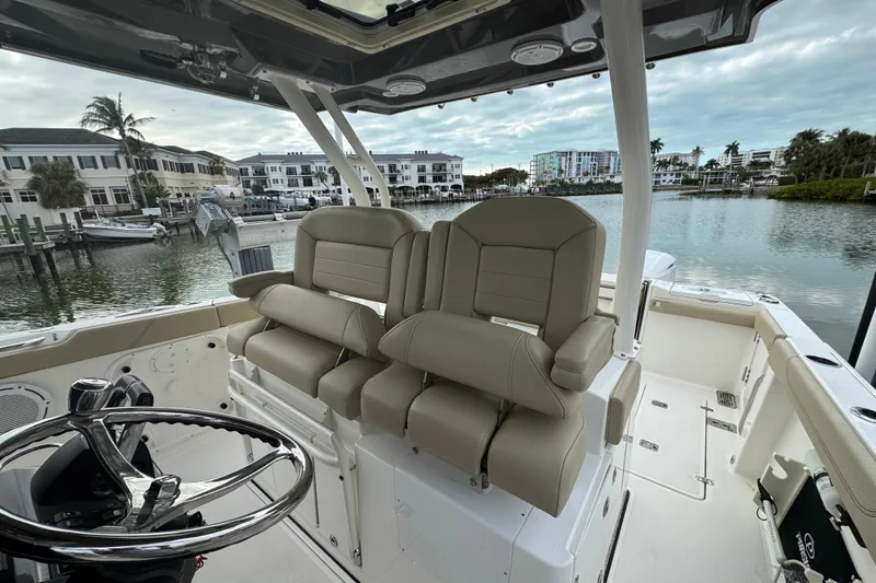 Slide: The Image of 2020 Pursuit S 328 Sport boat interior with helm and seating, docked in a marina. - 29
