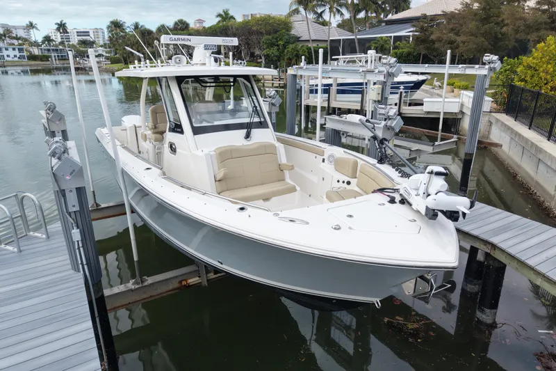Slide: The Image of 2020 Pursuit S 328 Sport boat docked in a marina, surrounded by water and palm trees. - 4