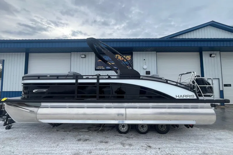 The Image of 2025 Harris Solstice 230 pontoon boat parked outside a blue and white building. - 1