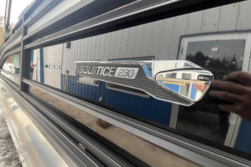 Slide: The Image of 2025 Harris Solstice 230 boat emblem on sleek exterior near a building. - 6