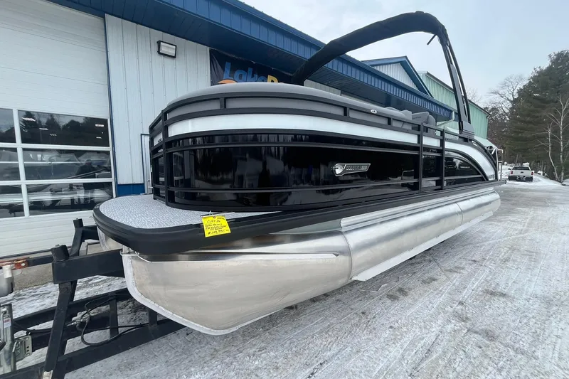 Slide: The Image of 2025 Harris Solstice 230 pontoon boat on snowy ground near a blue building. - 7