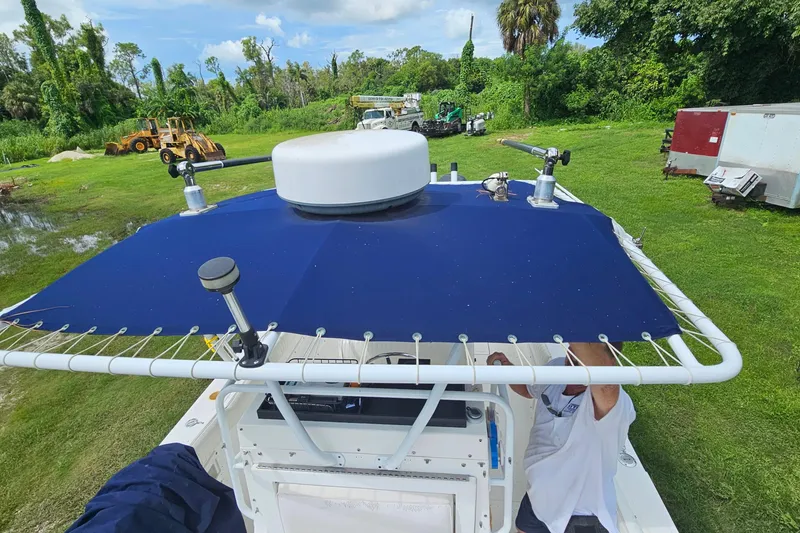 Slide: The Image of 1993 Marlin 350 Sportfish boat with blue canopy, parked on grassy area. - 29