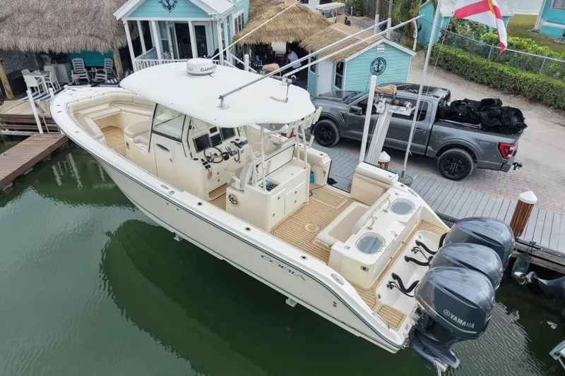 Slide: The Image of 2015 Cobia 344 Center Console boat docked, featuring triple Yamaha engines. - 0