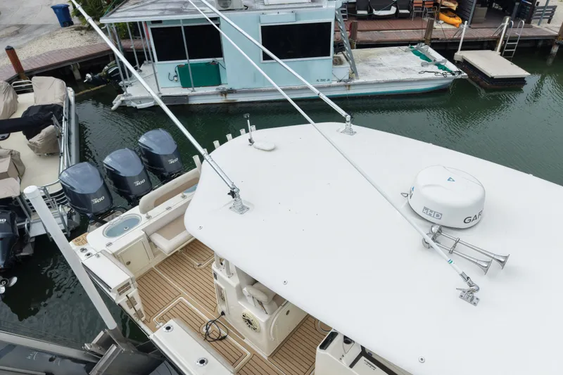 Slide: The Image of 2015 Cobia 344 Center Console boat docked with triple outboard engines. - 13