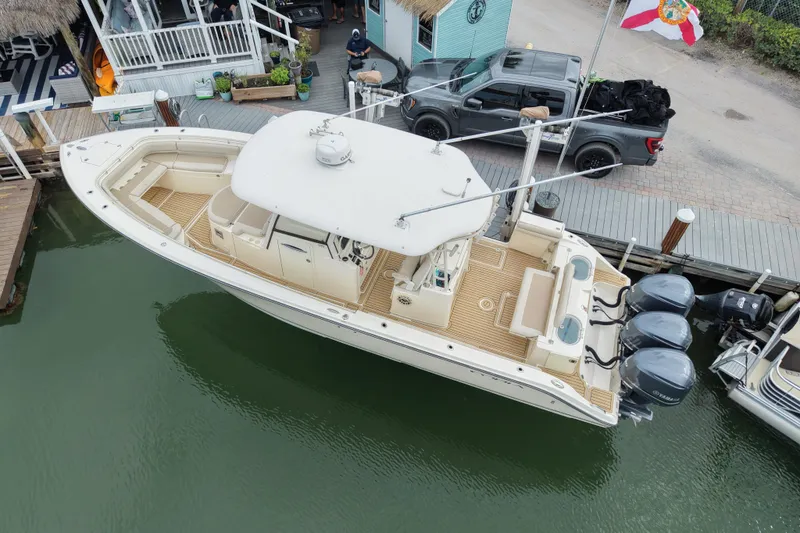 Slide: The Image of 2015 Cobia 344 Center Console boat docked, featuring triple outboard engines and spacious deck. - 3
