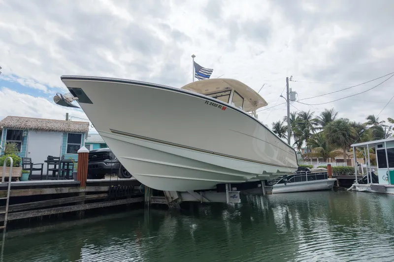 Slide: The Image of 2015 Cobia 344 Center Console boat docked near tropical waterfront homes. - 4