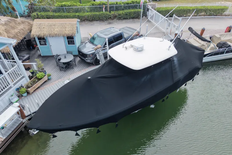 Slide: The Image of 2015 Cobia 344 Center Console boat covered, docked near a waterfront deck. - 8