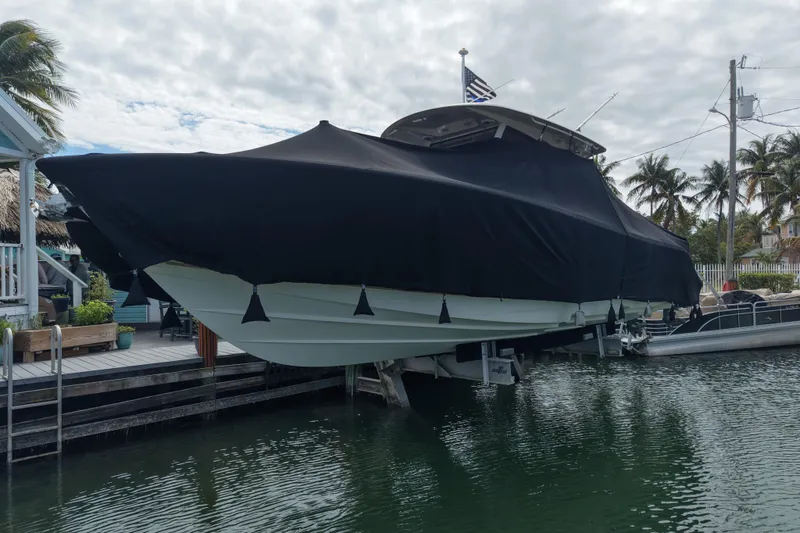 Slide: The Image of 2015 Cobia 344 Center Console boat covered and docked near palm trees. - 9
