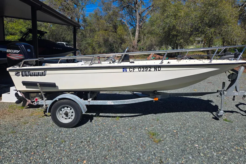 Slide: The Image of 1989 Wahoo 16.2 boat on trailer, parked outdoors, surrounded by trees. - 16
