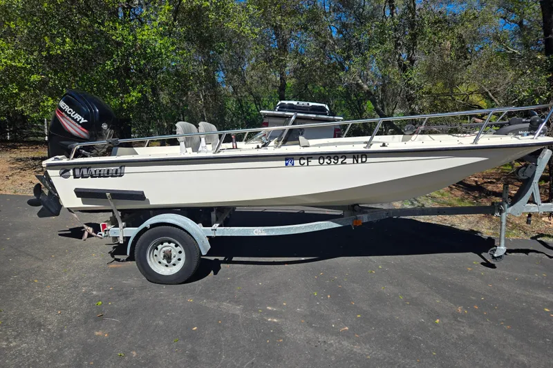 Slide: The Image of 1989 Wahoo 16.2 boat on trailer with Mercury outboard motor, parked outdoors. - 19