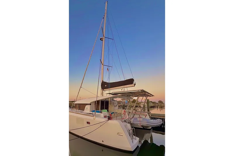 Slide: The Image of 2014 Lagoon 39 catamaran docked at sunset, featuring sails and dinghy. - 4
