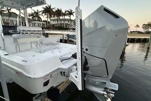 Slide: The Image of 2025 Contender 26 Bay boat with powerful outboard motor docked by waterfront homes. - 8