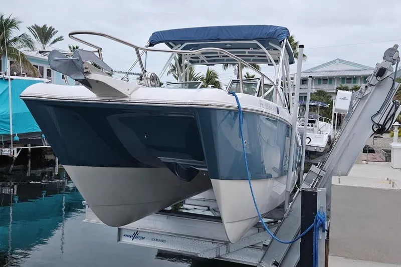 The Image of 2019 World Cat 255 DC boat on lift, dockside with palm trees in background. - 0