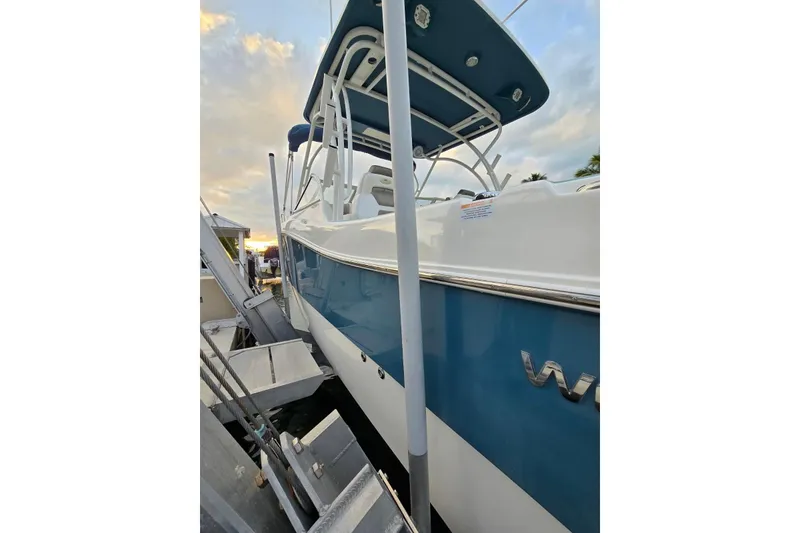 Slide: The Image of 2019 World Cat 255 DC boat docked at sunset, featuring sleek blue and white design. - 2