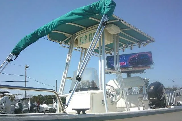 Slide: The Image of 2005 Sundance B22CX boat with green canopy, parked outdoors under clear blue sky. - 11