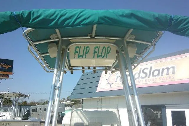 Slide: The Image of 2005 Sundance B22CX boat with "Flip Flop" name, green canopy, at a boat sales location. - 15