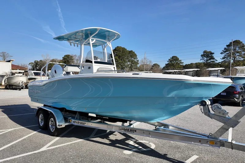 Slide: The Image of 2026 NauticStar 231 Hybrid boat on trailer, light blue hull, parked outdoors. - 3