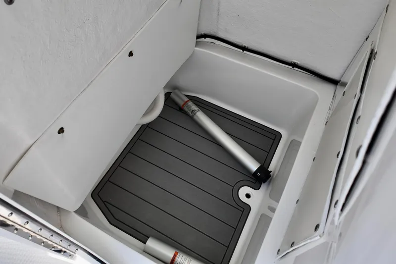 Slide: The Image of 2026 NauticStar 231 Hybrid boat storage compartment with gray flooring and metal support pole. - 6