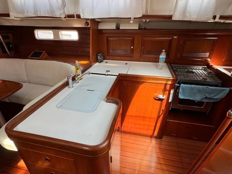 Slide: The Image of Interior of 2001 Beneteau Oceanis Clipper 473 yacht, featuring a cozy kitchen and seating area. - 15