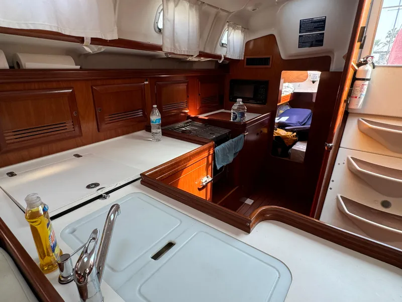 Slide: The Image of Interior of 2001 Beneteau Oceanis Clipper 473 yacht, featuring kitchen and cozy cabin area. - 24