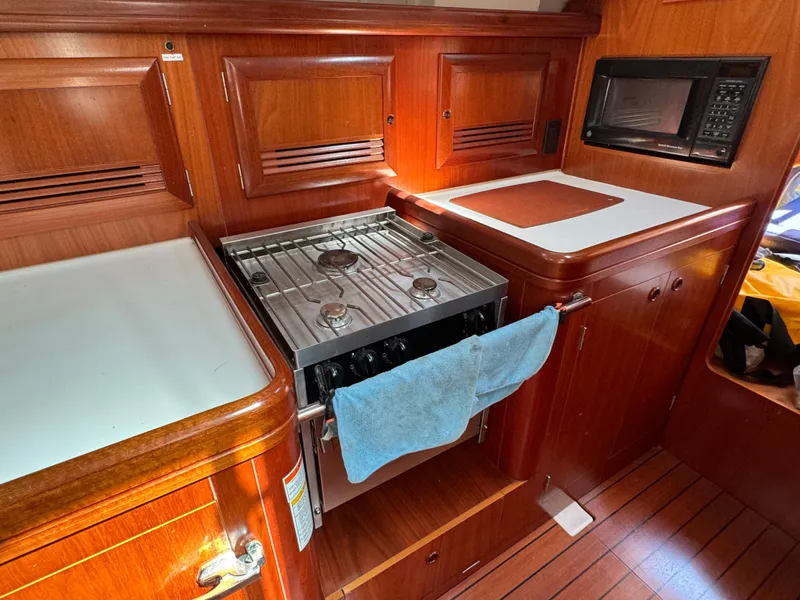Slide: The Image of Galley of 2001 Beneteau Oceanis Clipper 473 with stove, microwave, and wooden cabinetry. - 27