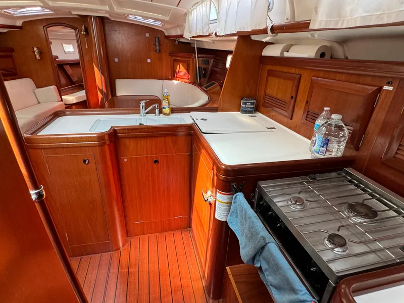 Slide: The Image of Interior of 2001 Beneteau Oceanis Clipper 473 yacht, featuring a wooden kitchen and seating area. - 28