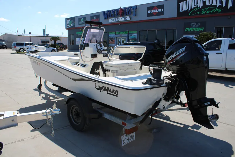 Slide: The Image of 2022 Mako Pro Skiff 15 CC boat with Mercury engine on trailer, parked outside dealership. - 2