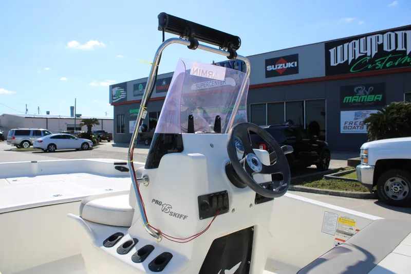 Slide: The Image of 2022 Mako Pro Skiff 15 CC boat at dealership, featuring steering console and seating. - 5