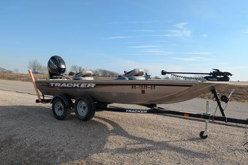Slide: The Image of 2017 Tracker Panfish 16 boat on trailer, parked on gravel road under clear sky. - 12