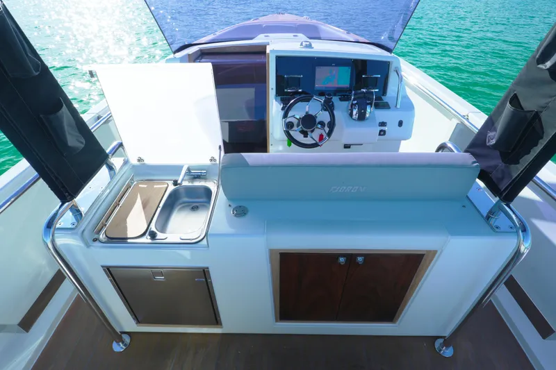 Slide: The Image of Helm and kitchenette area of 2018 Fjord 36 Xpress boat on water. - 28