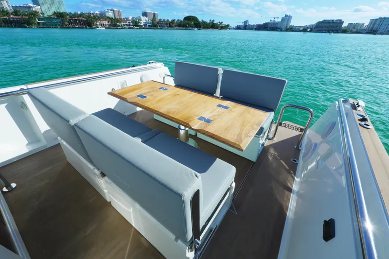 Slide: The Image of 2018 Fjord 36 Xpress boat with seating and table, overlooking turquoise water and cityscape. - 30
