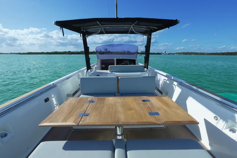 Slide: The Image of 2018 Fjord 36 Xpress boat with wooden table, cruising on turquoise waters under a clear blue sky. - 33