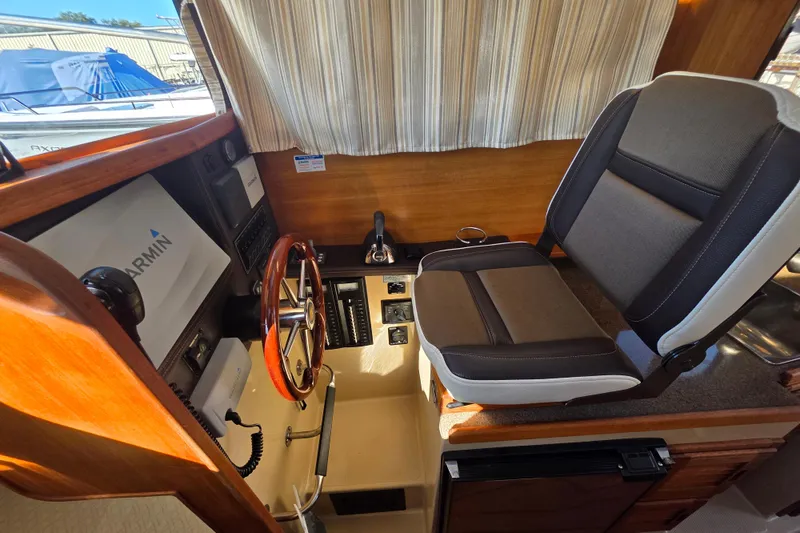Slide: The Image of 2017 Ranger Tugs R-27 helm with Garmin navigation, wood accents, and cushioned captain's chair. - 10