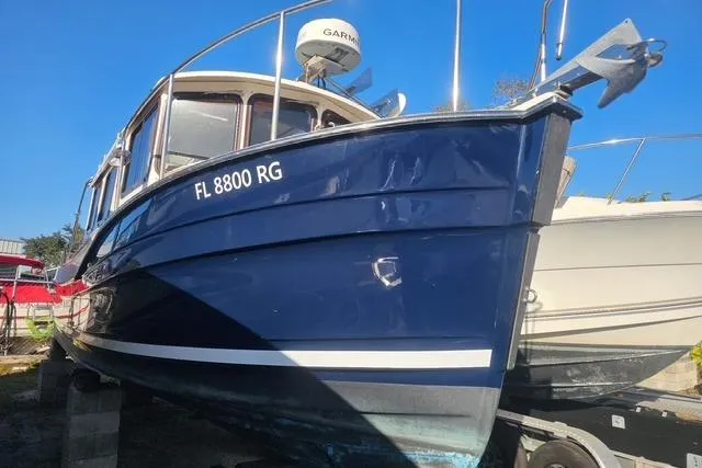 Slide: The Image of 2017 Ranger Tugs R-27 boat with blue hull, docked on land, sunny day. - 2