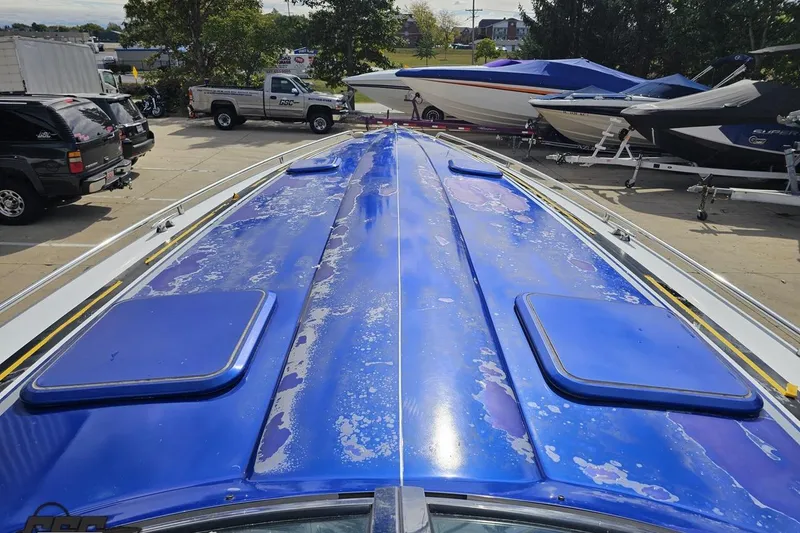 Slide: The Image of 2009 Formula 353 FASTech boat with weathered blue deck, parked among other boats. - 71