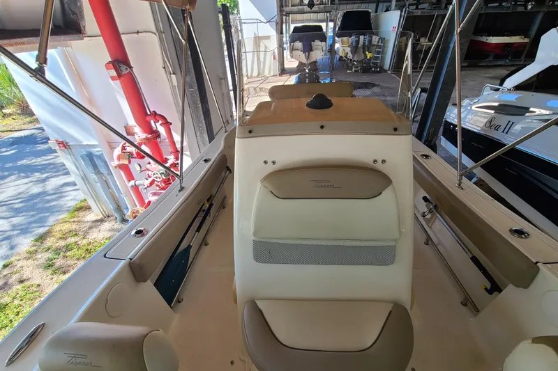 Slide: The Image of 2015 Pioneer 220 Bay Sport boat interior with seating and storage, docked in a marina. - 13