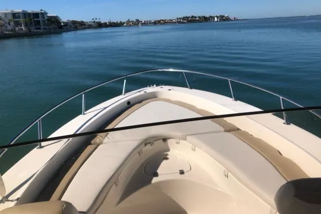 Slide: The Image of 2015 Pioneer 220 Bay Sport boat on calm water, showcasing spacious deck and seating. - 5