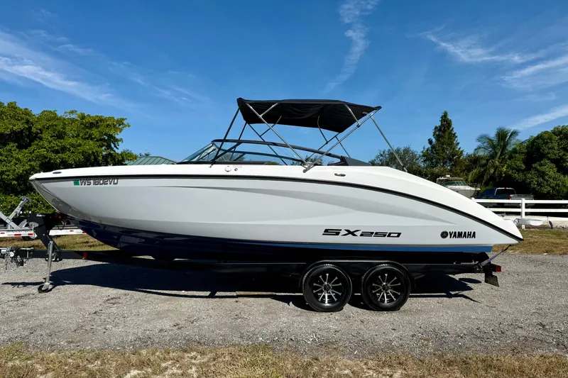 The Image of 2024 Yamaha SX 250 boat on trailer, parked outdoors under clear blue sky. - 0