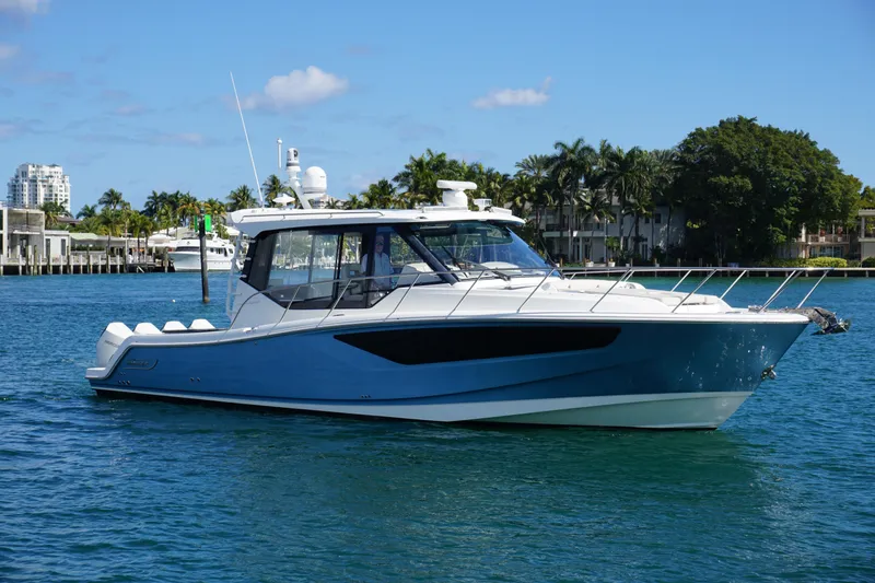 The Image of 2021 Boston Whaler 405 Conquest boat on clear blue water, surrounded by palm trees. - 0