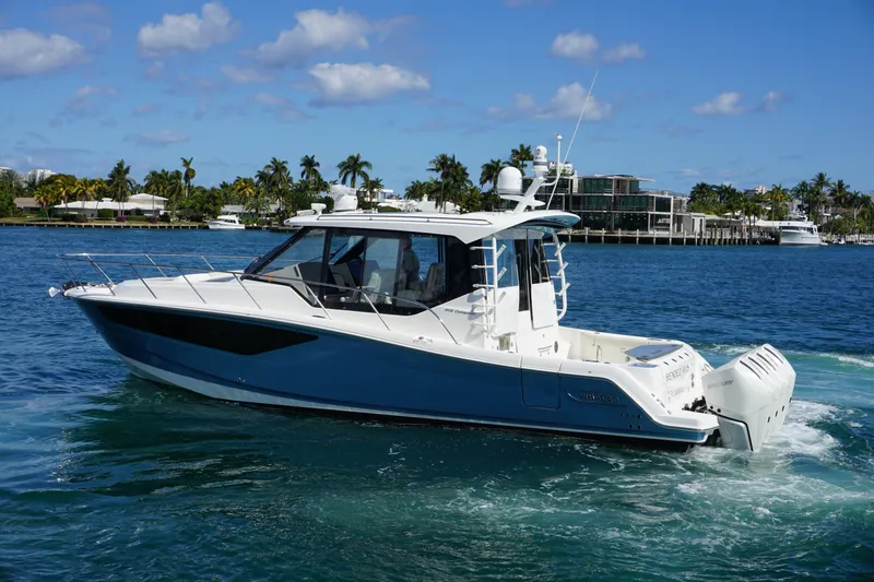 Slide: The Image of 2021 Boston Whaler 405 Conquest cruising on a sunny day with palm trees in the background. - 16