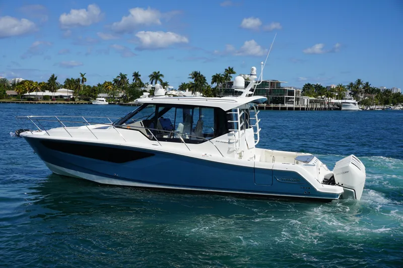 Slide: The Image of 2021 Boston Whaler 405 Conquest cruising on a sunny day with palm trees in the background. - 17
